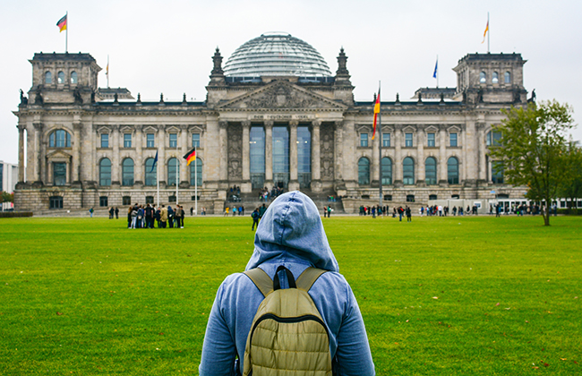 a young woman with backpack looking at Bundestag building in Berlin